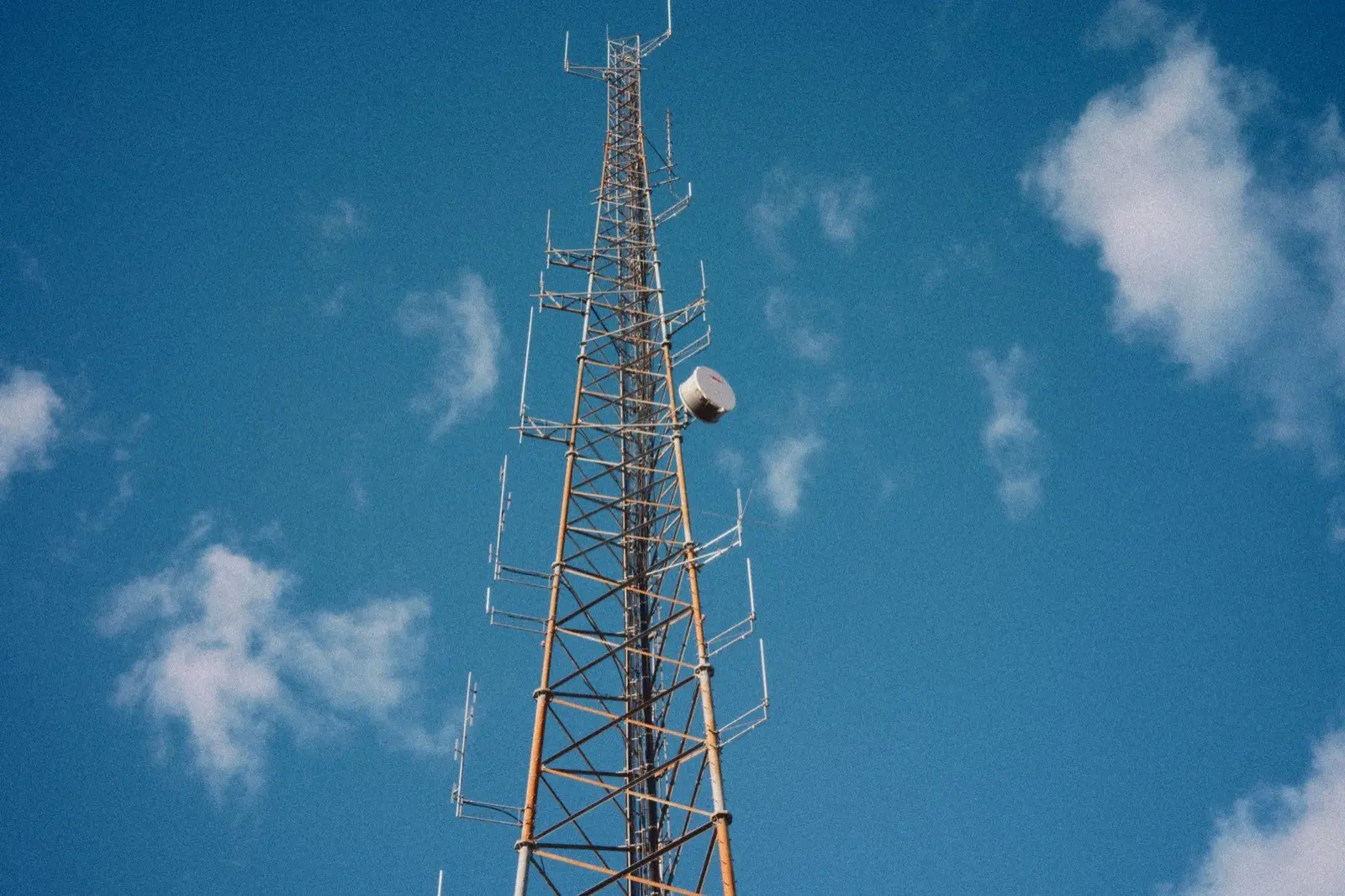 A communications tower seen from below against an open blue sky.