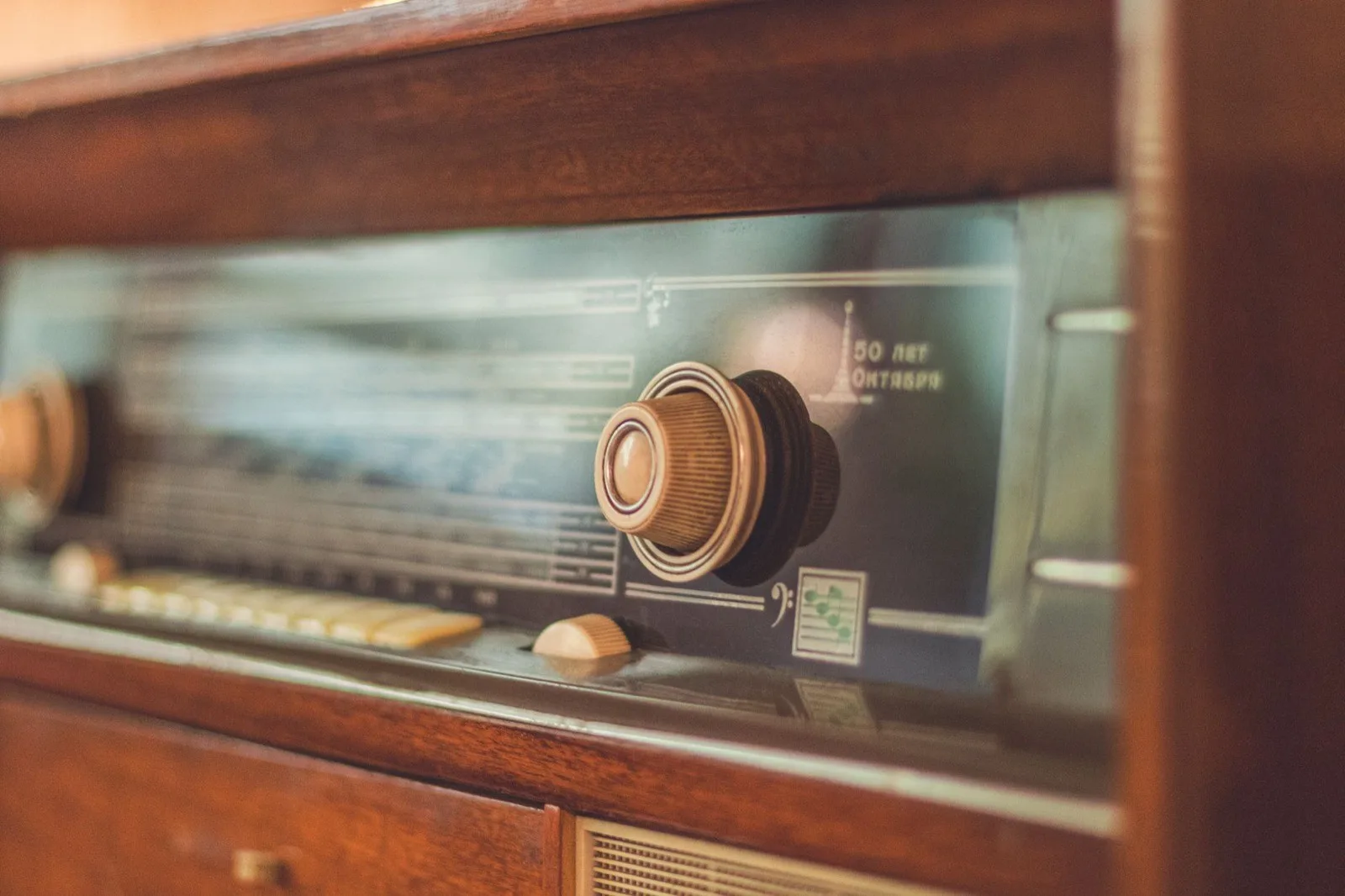 The illuminated dial of a wooden vintage radio, warm amber tones.