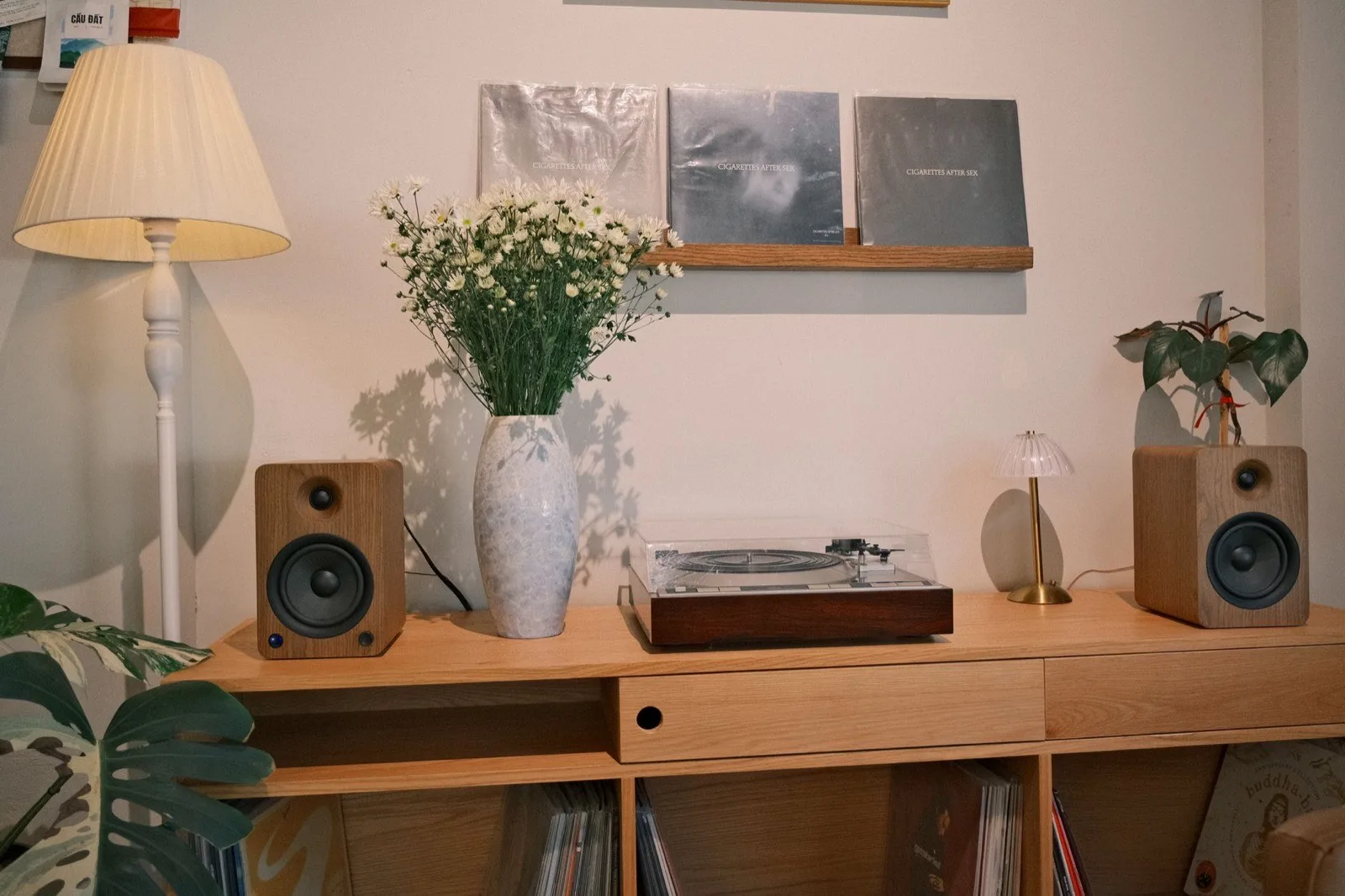 A turntable and bookshelf speakers on a wooden console in warm daylight.